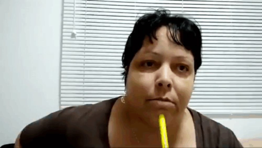 a woman with a pencil in her mouth looks at the camera