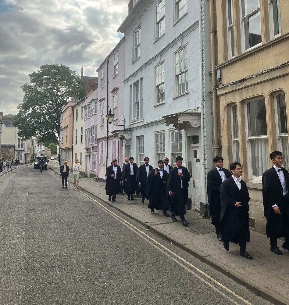 Students in gowns walking down Holywell Street in Oxford