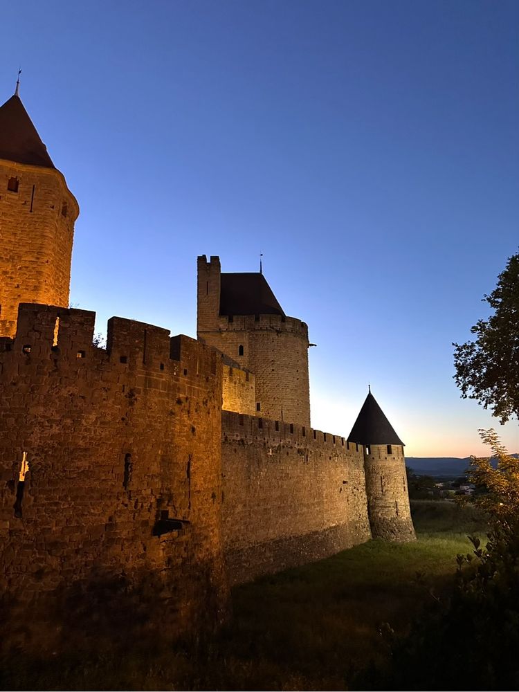 A view of the western ramparts of Carcassonne at sunset, the walls lit by floodlights