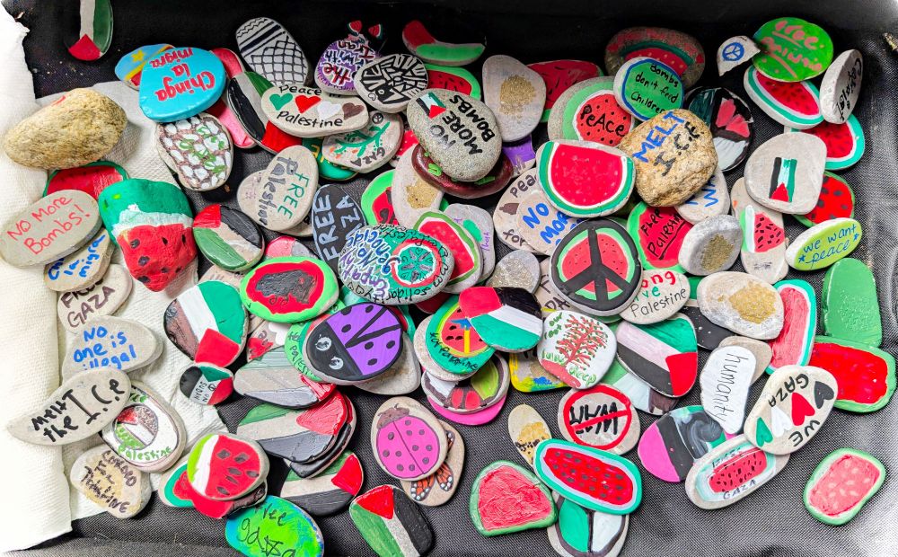 A pile of rocks painted with bright colors, and messages for Palestinian liberation. 