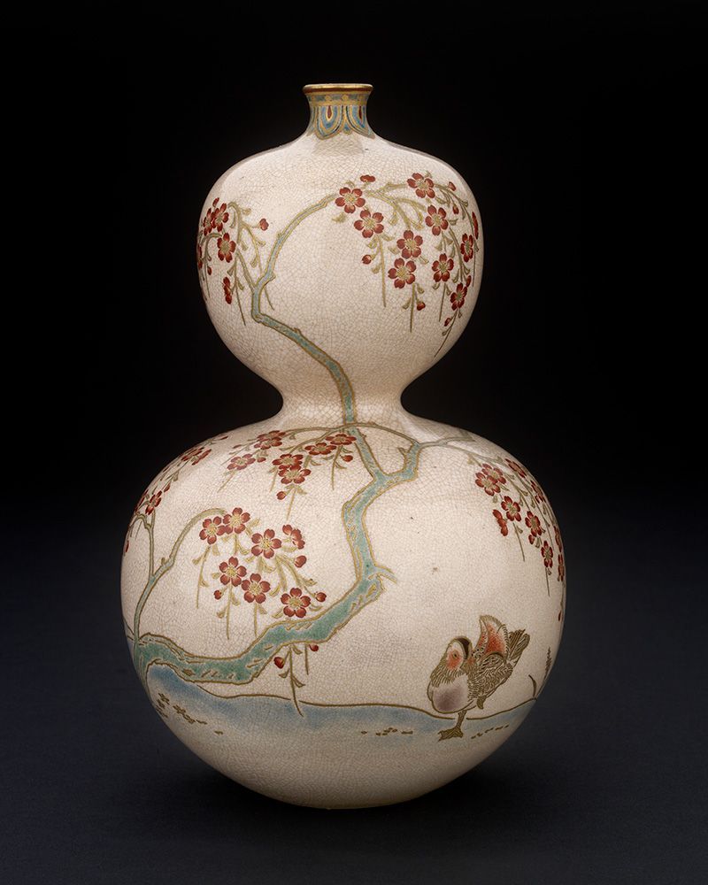 A photograph of the vase, a double-gourd form decorated with overglaze enamels. This photo shows a duck ruffling its feathers under a cherry blossom branch