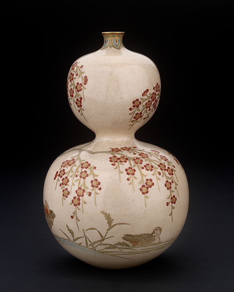 A photograph of the vase, a double-gourd form decorated with overglaze enamels. This photo shows a duck sitting in water under a cherry blossom branch