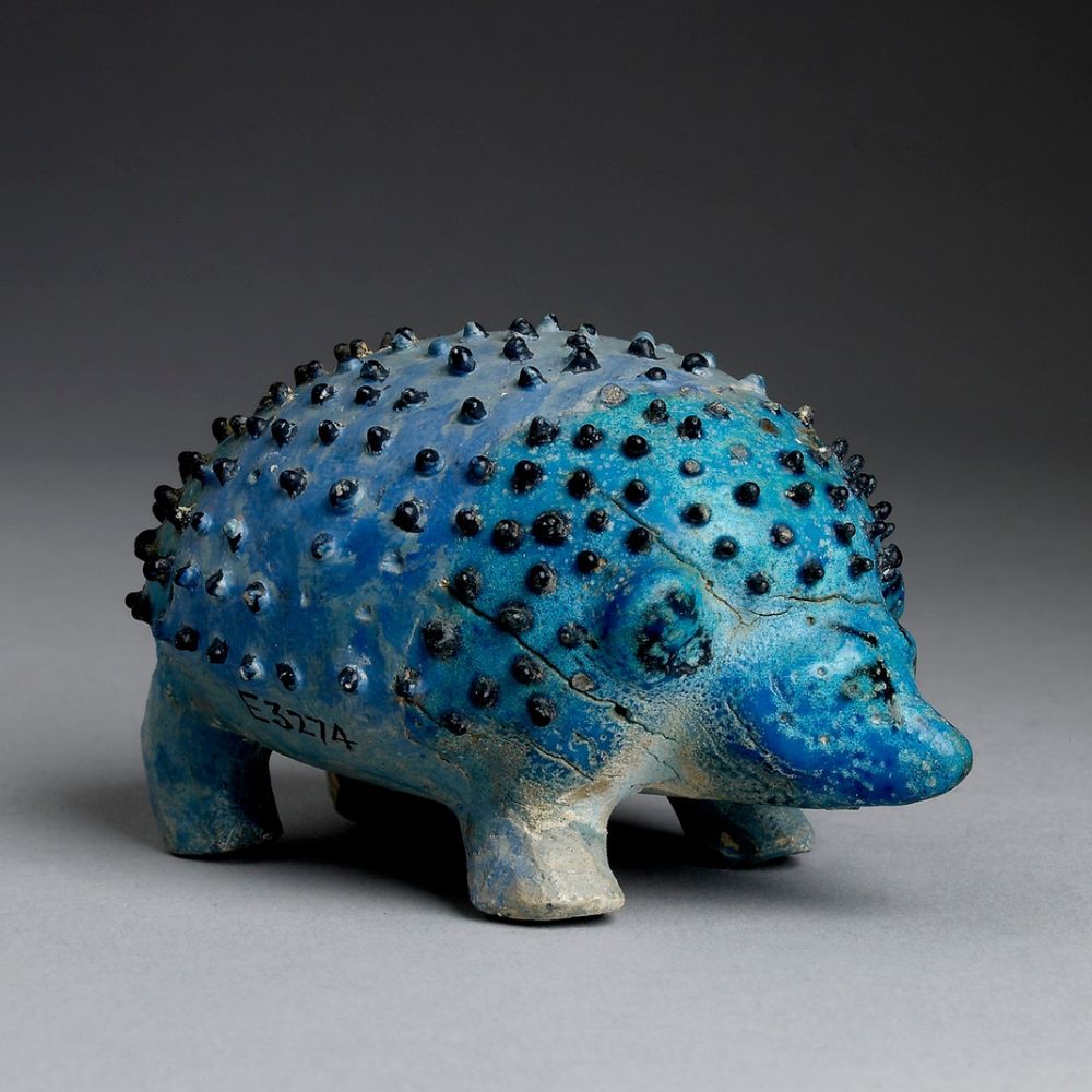 Tiny blue figurine of a hedgehog, with black spikes, made in Egypt about 1,500–1,300 BCE.
