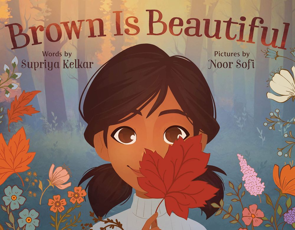 This is the book cover for Brown is Beautiful written by Indian American author Supriya Kelkar and Kashmiri-American Noor Sofi. The cover features a young brown-skinned girl of South Asian descent holding a brown leaf which covers part of her face. She is smiling and is surrounded by flowers.