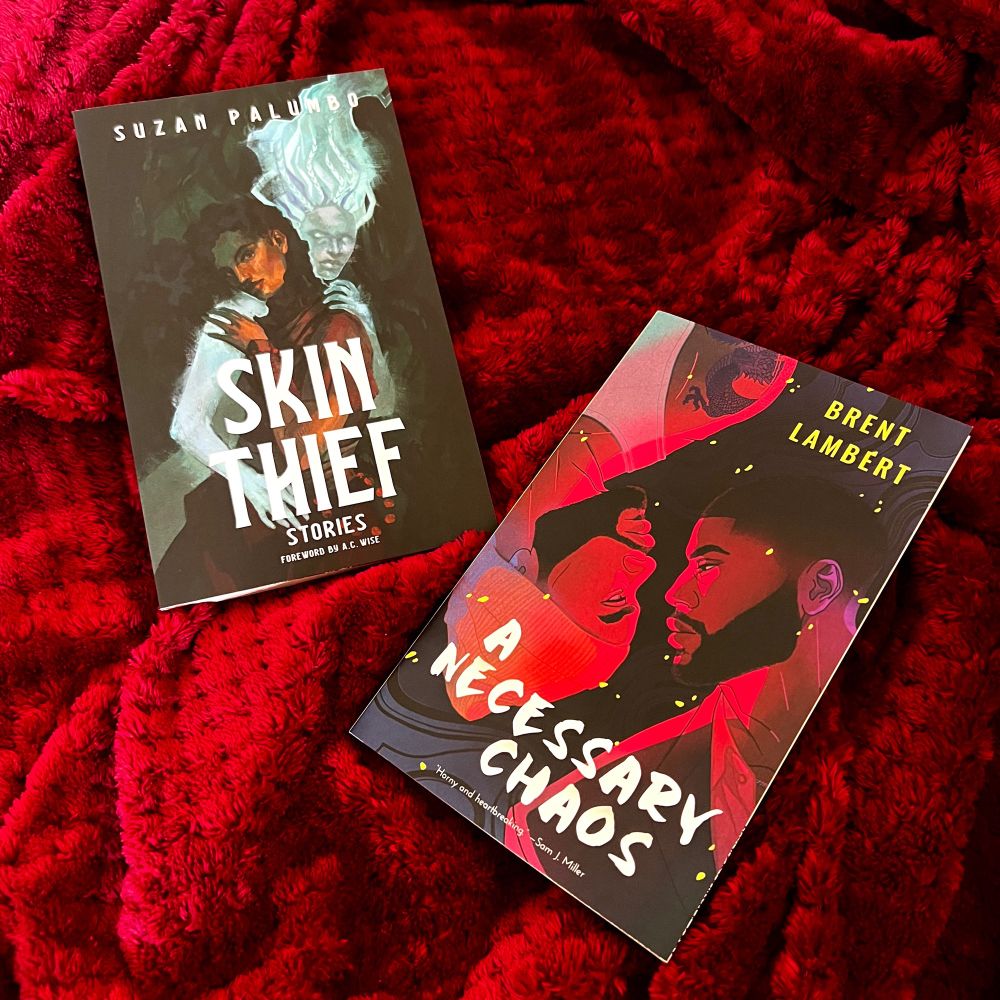 [image desc: a copy of SKIN THIEF by Suzan Palumbo and A NECESSARY CHAOS by Brent C. Lambert on a soft red back drop.]