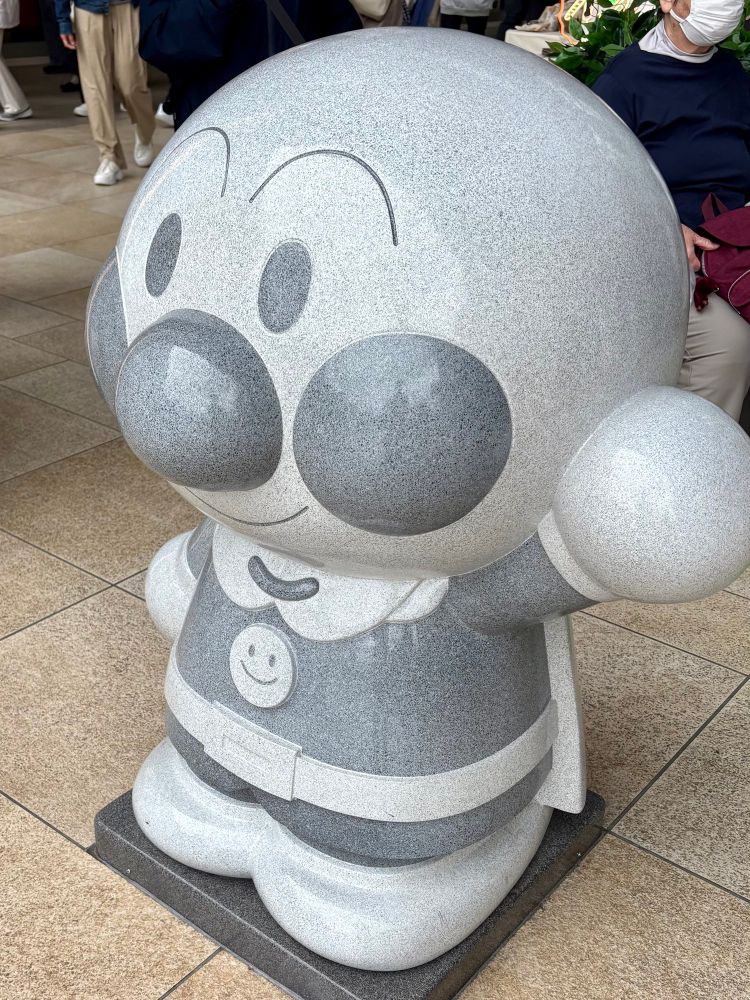 仙台駅自由通路に設置されていた、全身がグレーの石でできたアンパンマン像。全高1m弱。固まった微笑みを浮かべている。