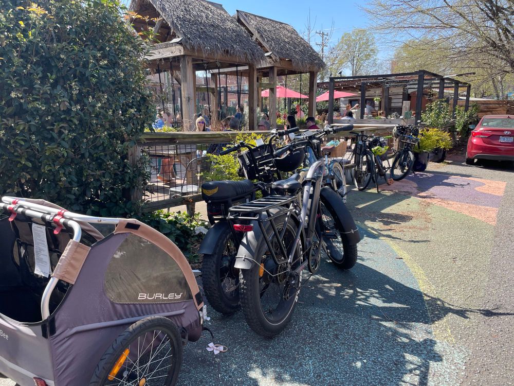 several bicycles and bike trailers parked in front of a crowded outdoor patio