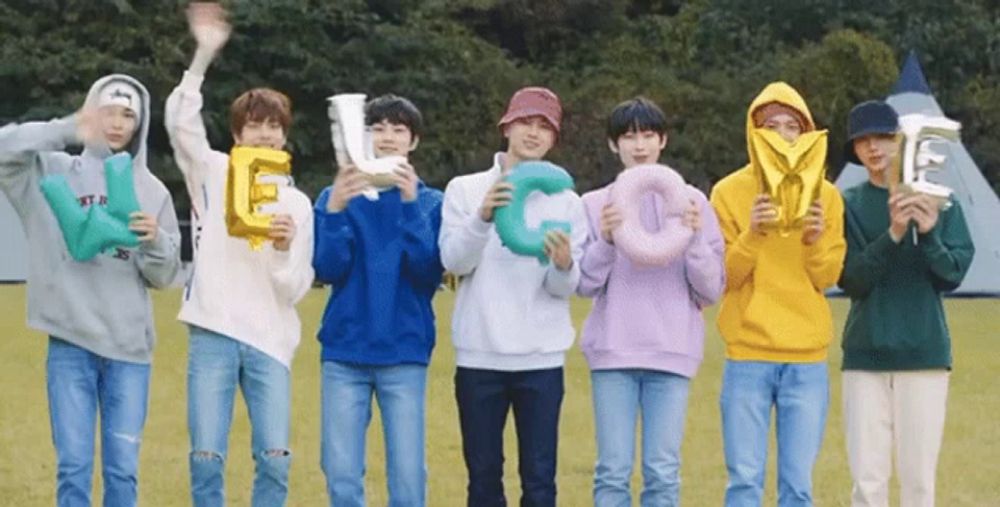 a group of young men are standing in a field holding balloons that spell out the letters e and c