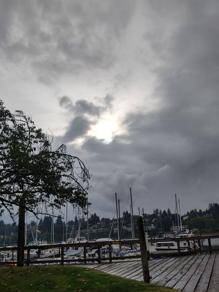 Striking appearance of the sun bursting through overcast clouds above a harbor.
