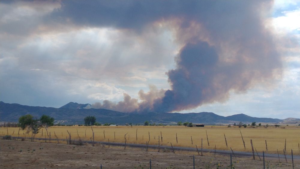 Smoke billowing up against a cloudy sky. Taken from a few miles away from the fire. 