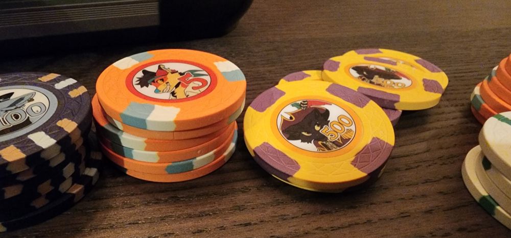 Close-up photo of the orange 5 point chip and yellow 500 point chip. The yellow chip features a drawing of AWU mascot Price dressed in pirate garb.