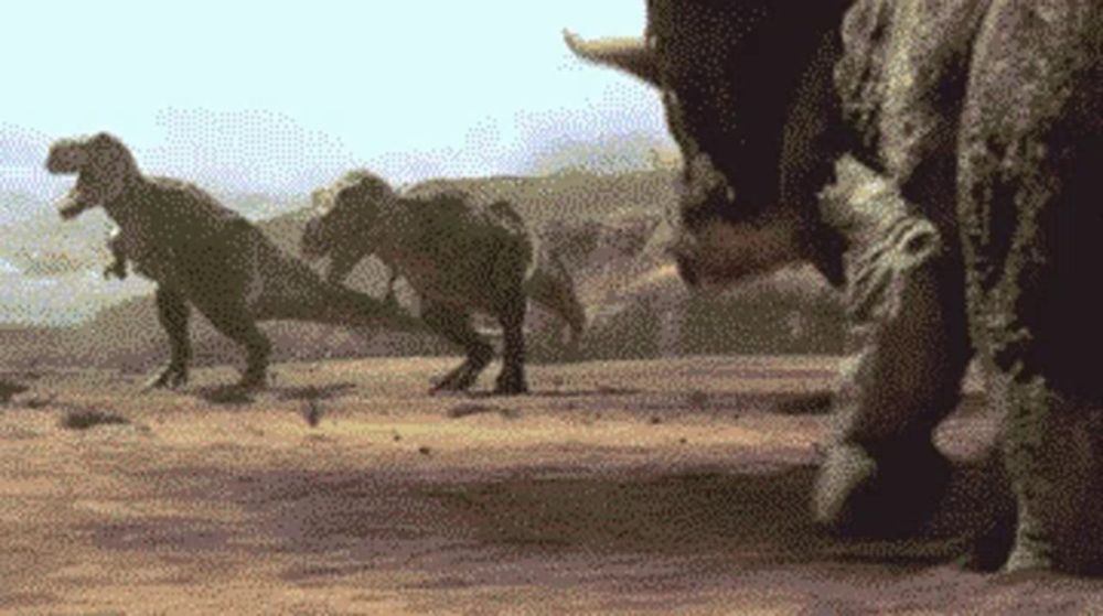 a group of dinosaurs are walking across a dirt field in the desert .