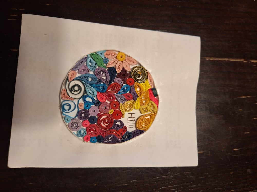Paper quilling is the art of rolling paper strips into different shapes. I used a wide range of colors, from blues and purples to yellows and reds. In the remaining space, I wrote 