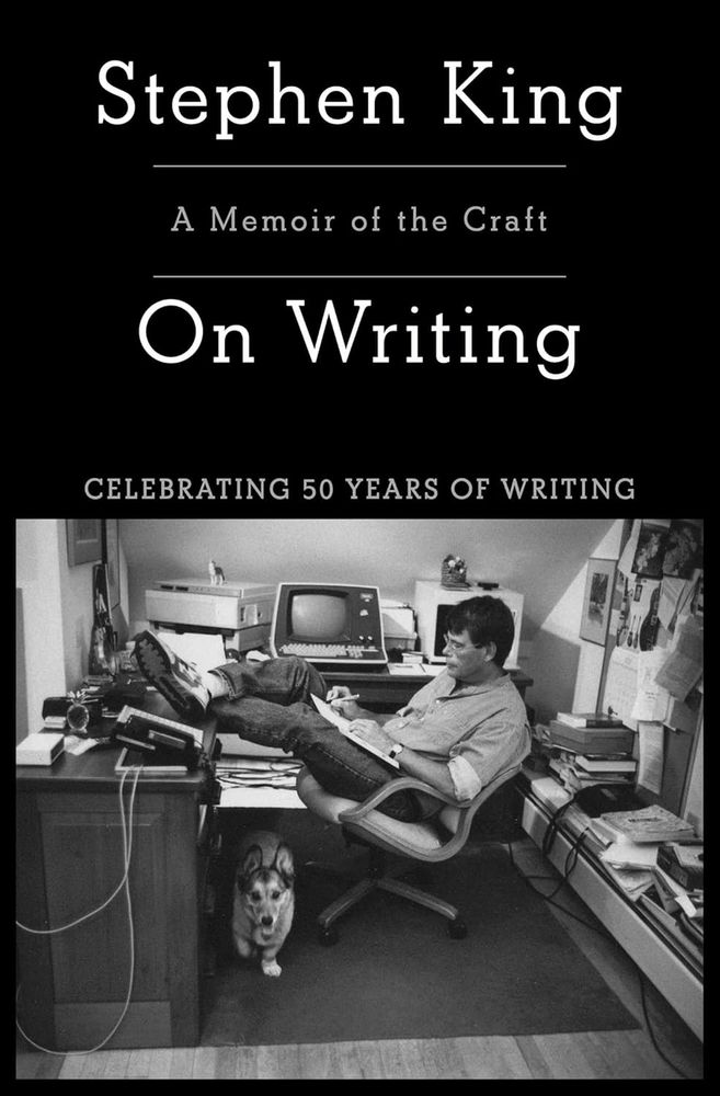 On Writing: A Memoir of the Craft by Stephen King book cover. Celebrating 50 years of writing. A picture of Stephen King writing at his desk with his propped up on the table and his dog underneath.