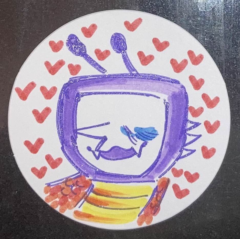 [ID: A pin button with the design drawn in markers. It depicts a smiling TV headed creature, with the scaled neck of a dragon, surrounded by hearts. end ID] 