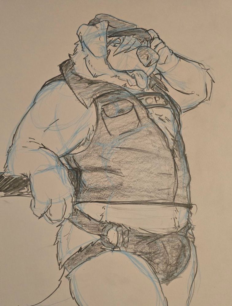 Toby leaning against a wall, wearing a series too harness and a leather outfit.