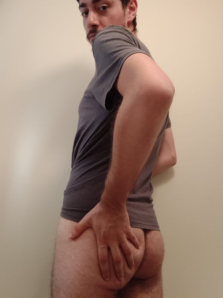 Me turned against the wall 45°, naked from the waist down and holding my left butt cheek with my hand.