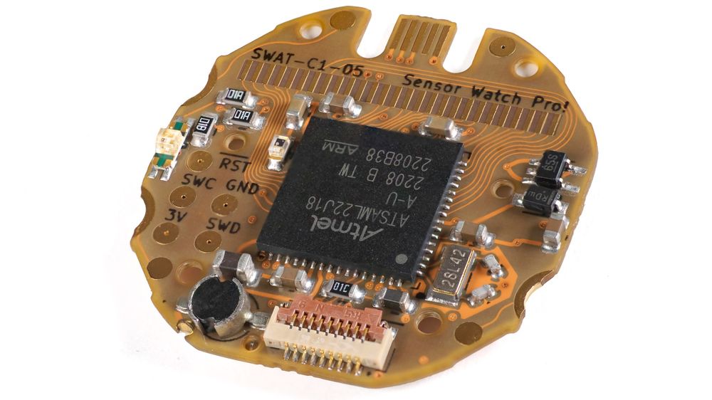 Photo of a small round circuit board titled “Sensor Watch Pro”