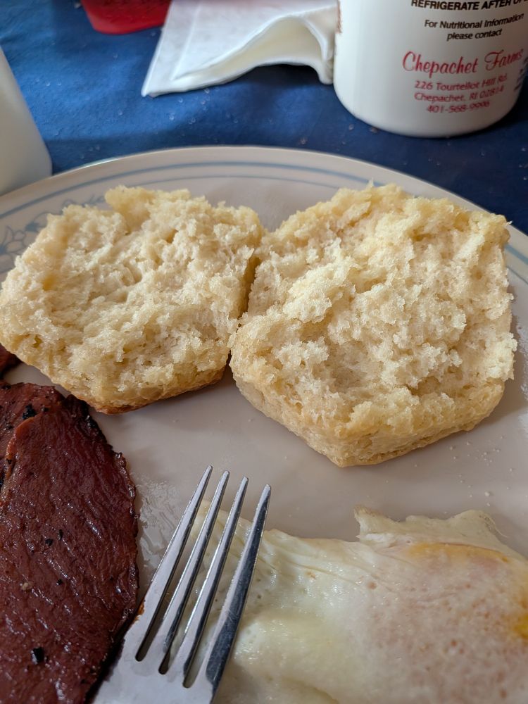 One of those biscuits split on a plate with an egg and bacon nearby 