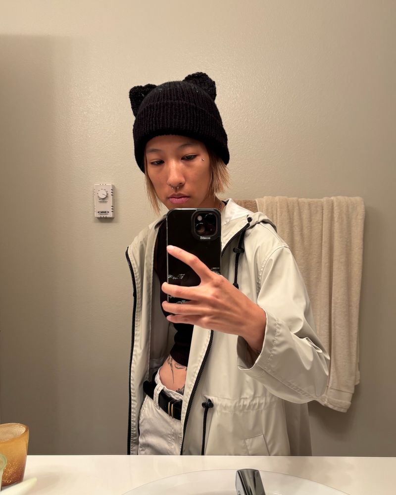 person wearing a cat ear beanie taking a mirror selfie