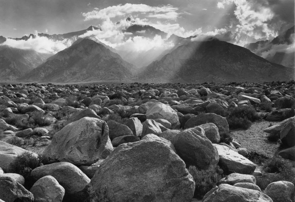 A photo of rocks with mountains and shafts of light in the background