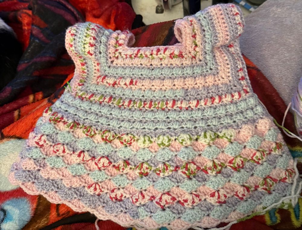an in-progress crochet project - baby dress, blue, pink, purple, and floral