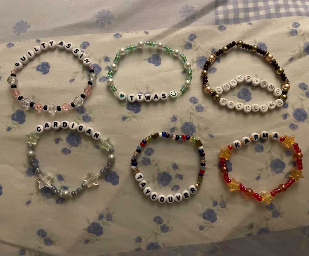 friendships bracelets that say cardigan, guilty as sin, taycouver, champagne problems and karma