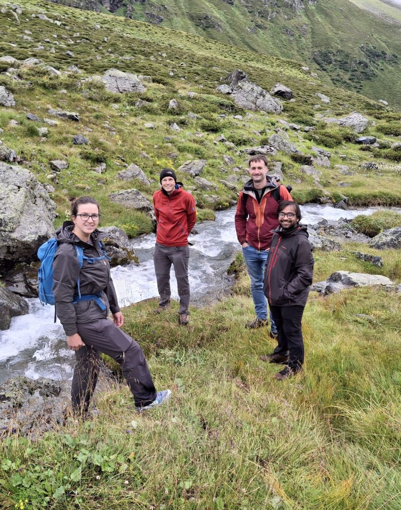 A group of hydrologists are standing next to a mountain stream.