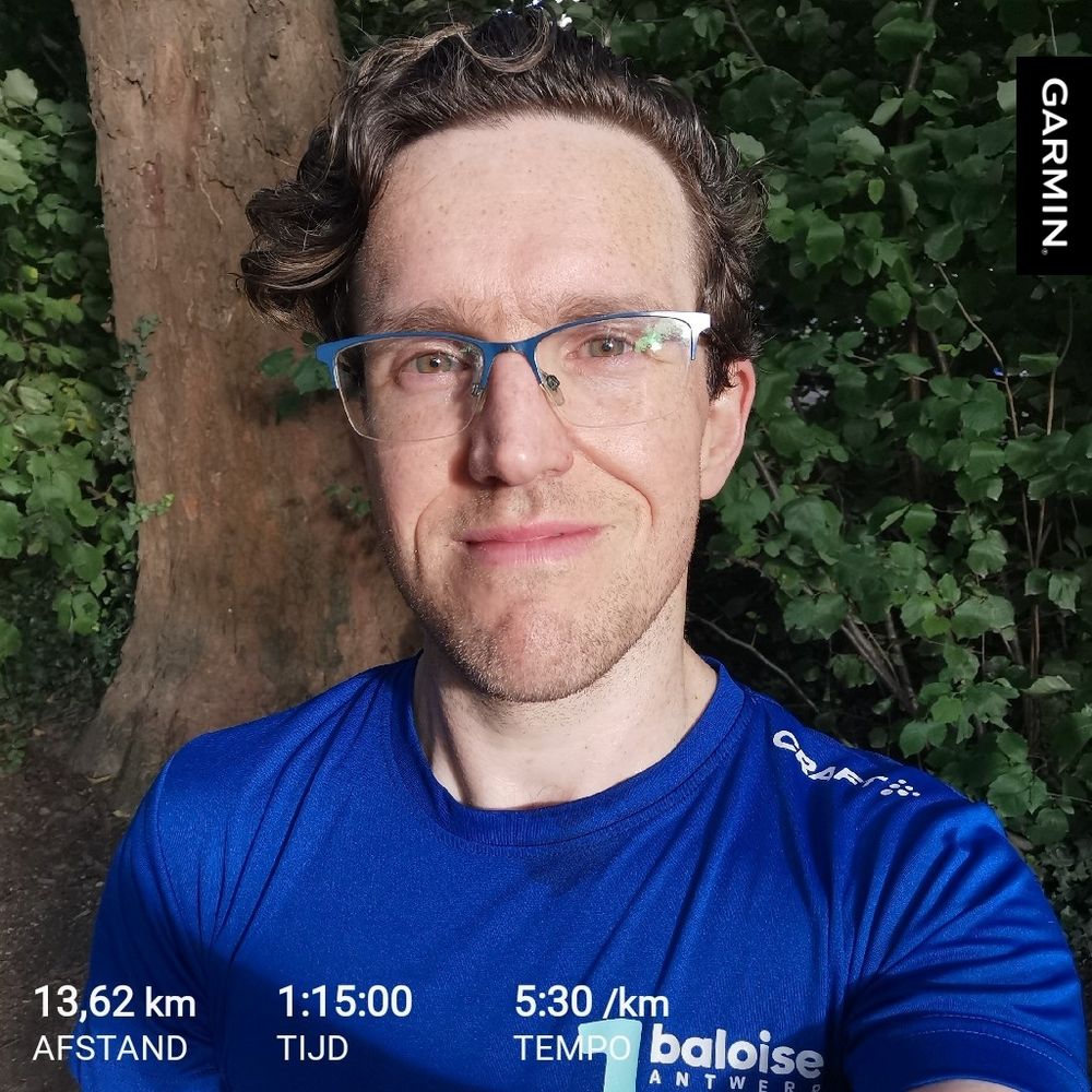 Selfie met onderaan data van de laatste hardlooptraining van Pieter Van der Schoot. Hij liep 13,62 km binnen 1 uur en 15 minuten. Dat is een tempo van 5 minuten en 30 seconden per uur. Pieter draagt een bril en een blauw T-shirt van de Baloise Antwerp 10 Miles. 