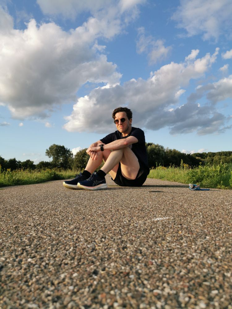 Pieter Van der Schoot zit op het asfalt na een training hardlopen in de zomer. 