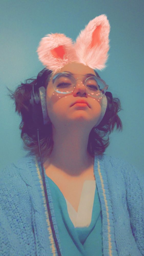 a dramatic profile shot of Faerie herself, wearing headphones and her classic pink bunny filter