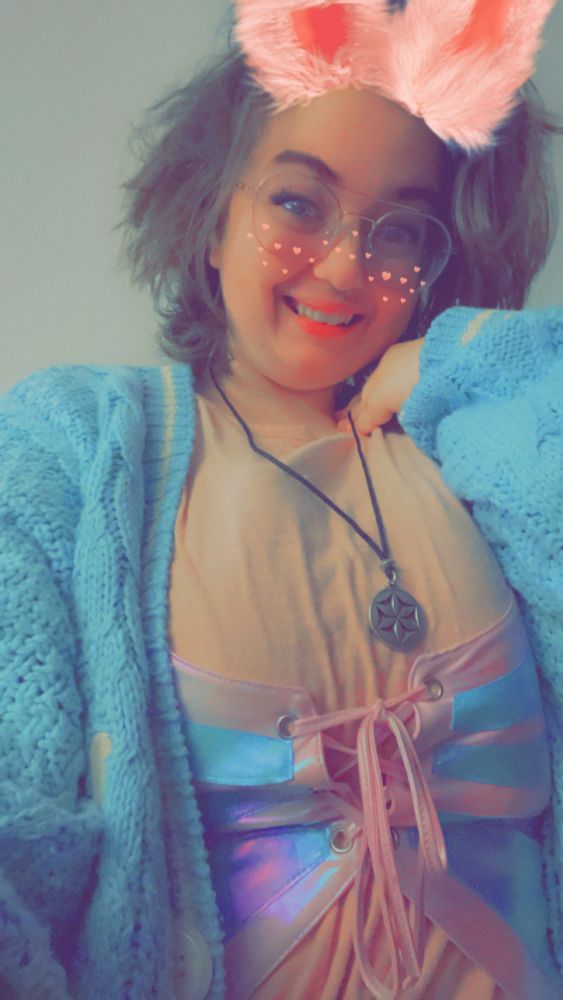 a girl with a bunny filter grinning and showing off a flower of Aphrodite necklace around her neck.