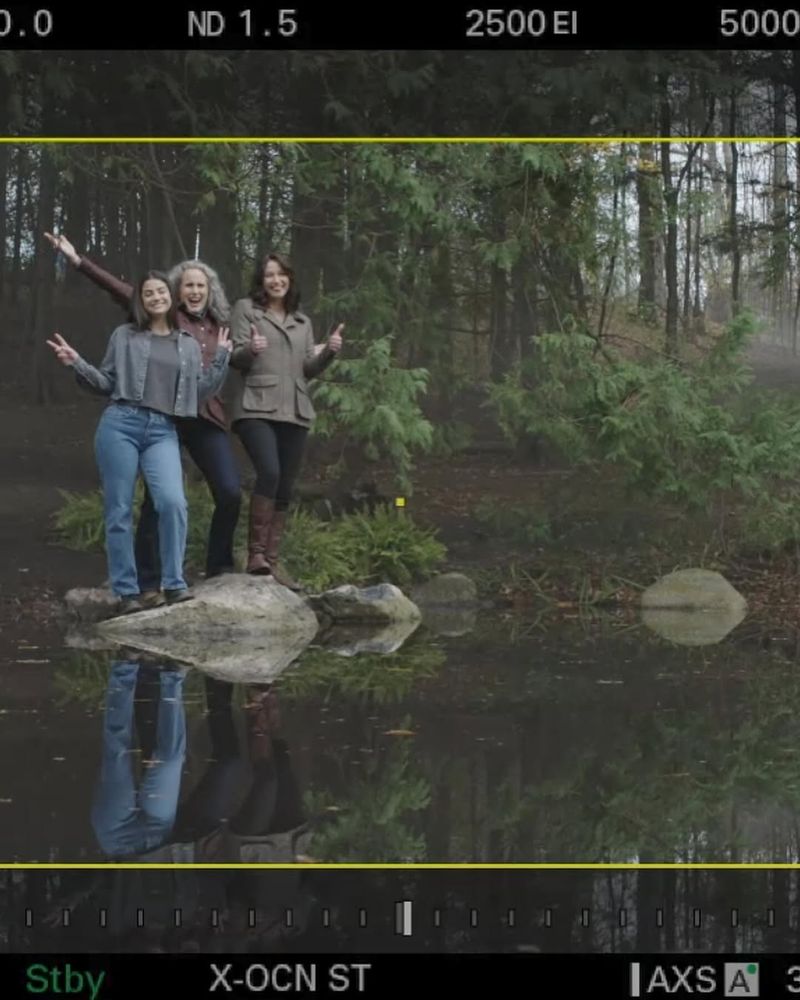A bts shot shows Sadie, Andie and Chyler at the ponds edge