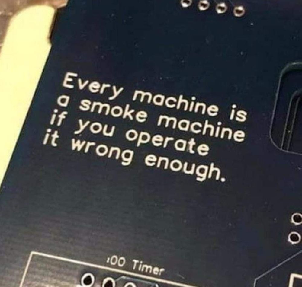 Back of some sort of device with holes to plug jacks into. Printed on the black surface is:
"Every machine is
a smoke machine
if you operate
it wrong enough"