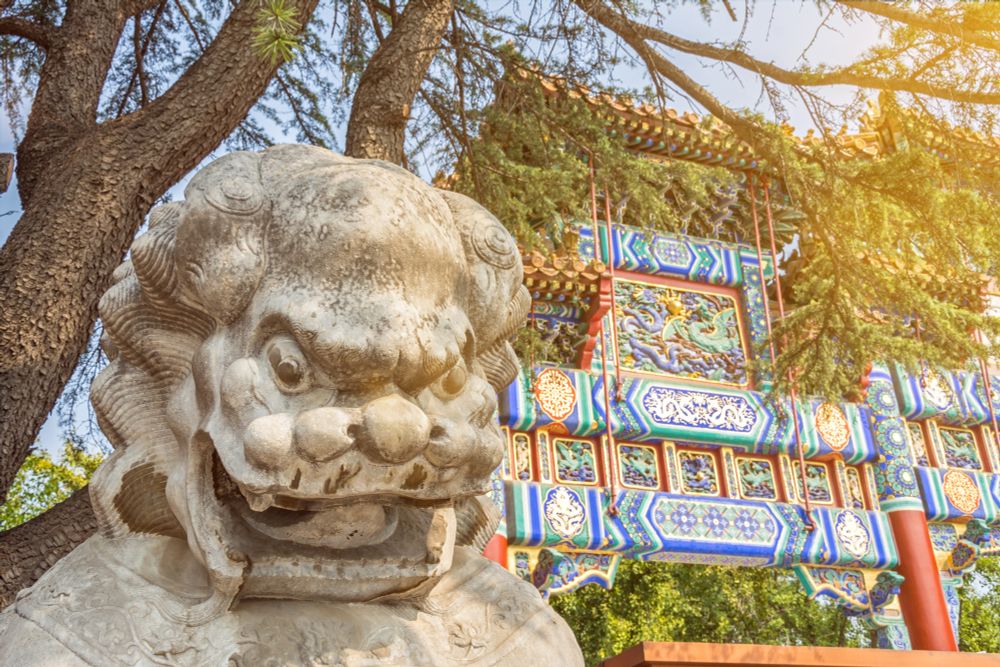 Steinstatue eines Löwen vor einem bunten Buddhistischen Tempel in Peking in China 
