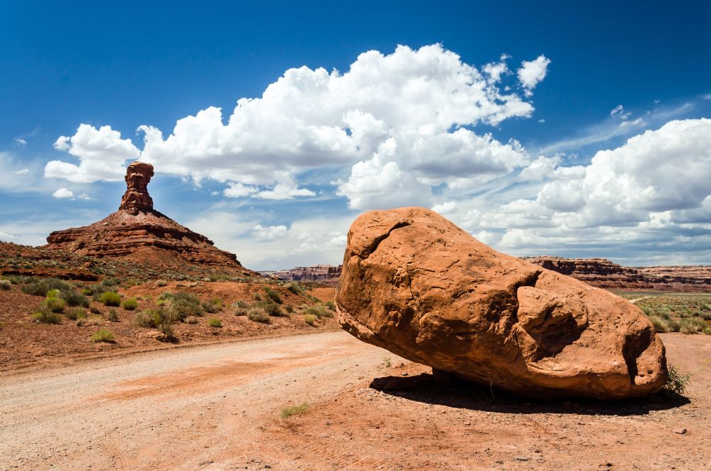 View of the red desert in the Valley of the Gods with a large rock in the foreground 