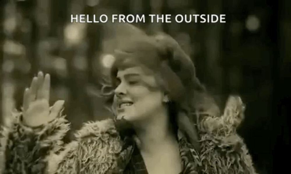 a woman in a fur coat is waving her hands in a black and white photo with the words `` hello from the outside '' .