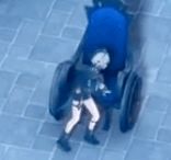 a person is sitting in a blue stroller on the ground .