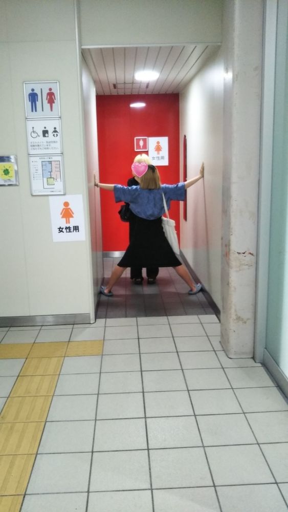 トイレの入り口で大の字で立つかのじょと通せんぼされるかのじょの元かのの写真。