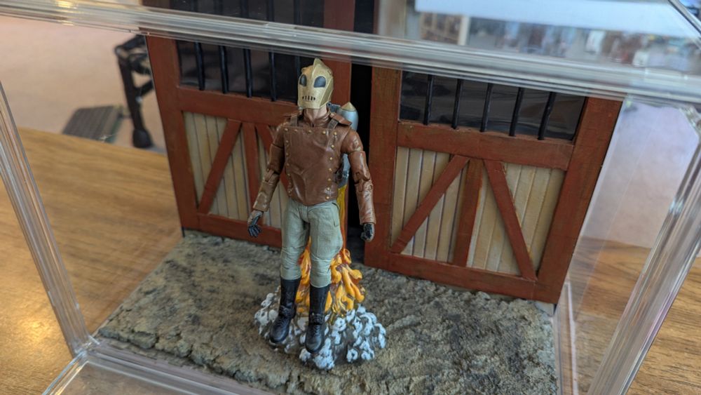 Diorama of the Rocketeer in front of hangar doors.