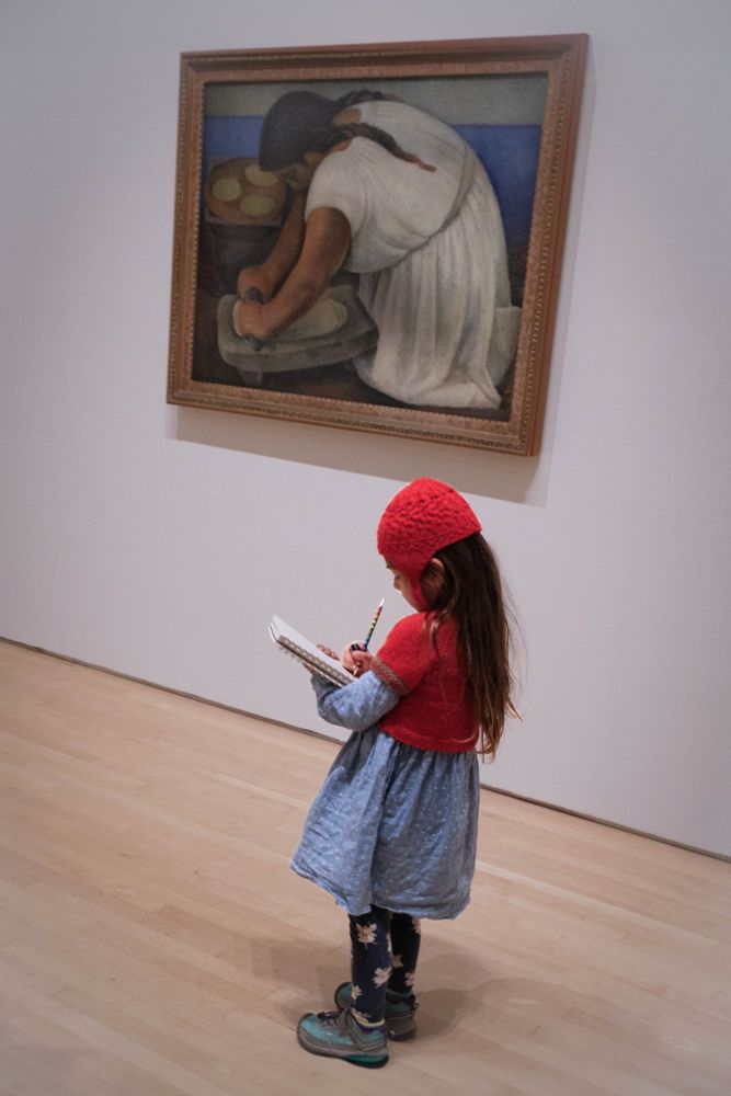 Little girl in museum sketching in front of the Diego Rivera painting "The Grinder"