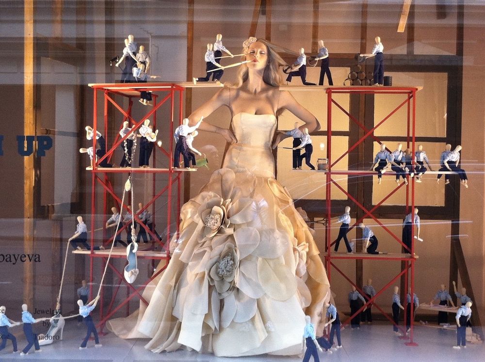 Kleinfield’s window display of a full-size bride mannequin being prepared for her wedding by wooden artist mannequins on small construction scaffolding