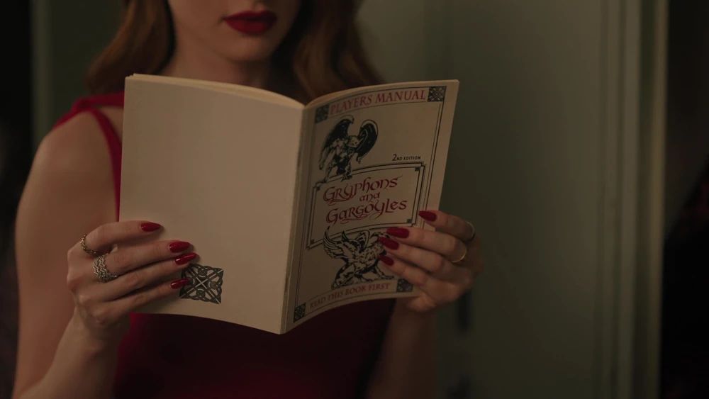 Cheryl from Riverdale holding a copy of Gryphons and Gargoyles, cover facing the viewer, which I am clearly trying to mimic pretty closely.