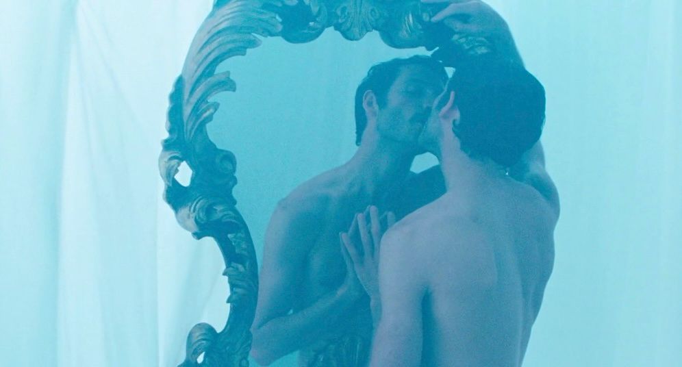 In a dreamy light blue scene, Valentin (Pierre Emo), kisses his own reflection in a large ornate mirror while nude. Very reminiscent of Narcissus.