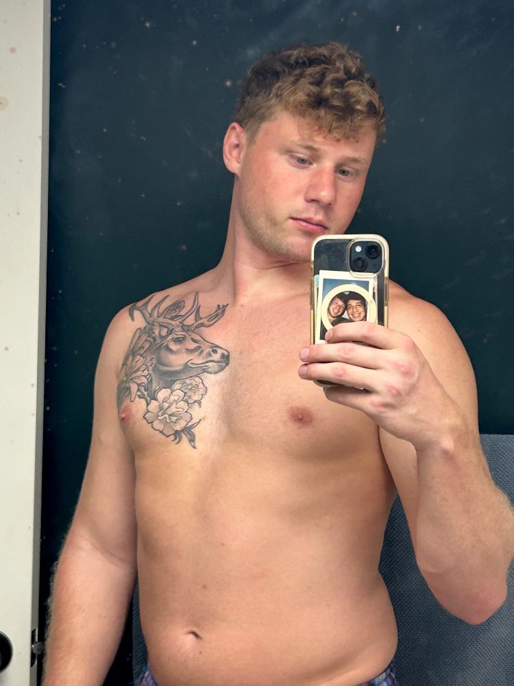 alolan9tails posing in the bathroom mirror after a workout against a dark green backdrop