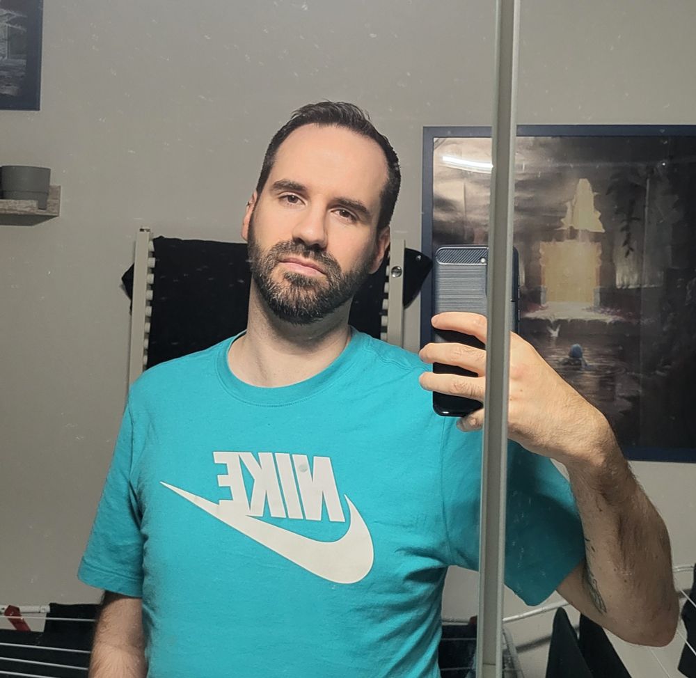 Iki schaut erschöpft vom Tag in den Badezimmerspiegel. Er trägt ein türkisblaues Nike-Shirt.