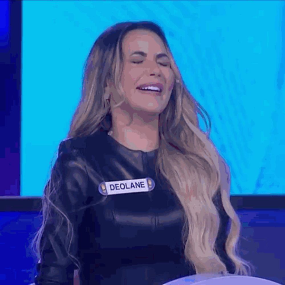 a woman wearing a black leather jacket and a name tag that says deolane is laughing .