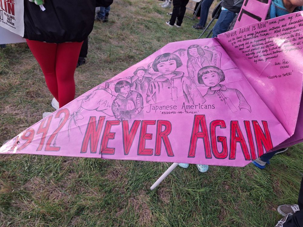 One wing of the origami crane says, "1942 Never Again" with drawings of Japanese American children, and part of the body says, "Never Again is Now" with historical details written below.