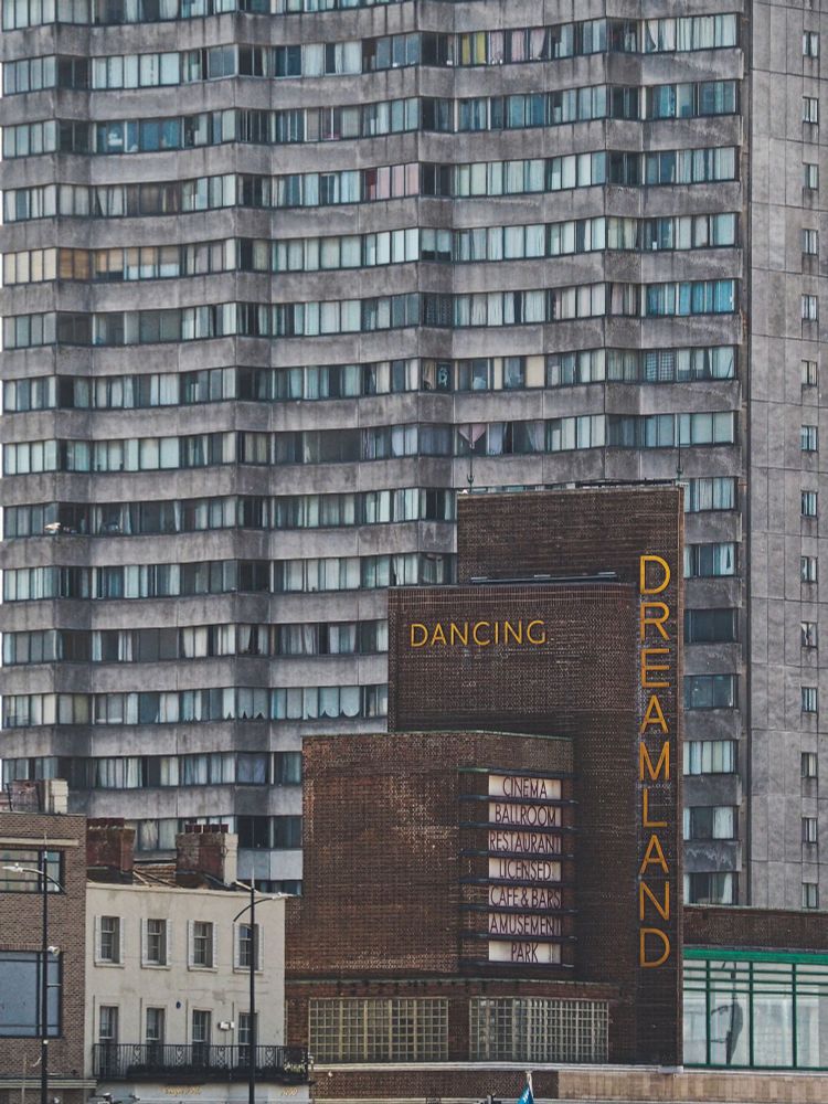 A long lens shot of the Dreamland facade with the yellow lettering running vertically down the brickwork. Compressed behind is the grey concrete Arlington Tower block. Lots of windows to peer into.