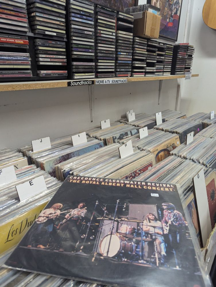 A vinyl record of Creedence Clearwater Revival recorded from The Royal Albert Hall Concert lays on top of multiple boxes of alphabetized vinyl records.